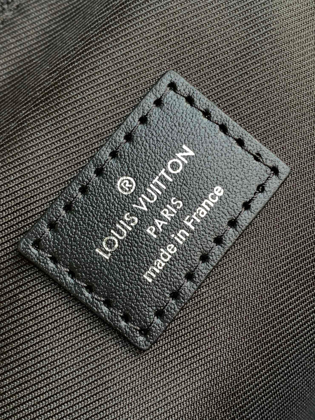 Leather brand tag on handbag with stitched border and text 'made in France'
