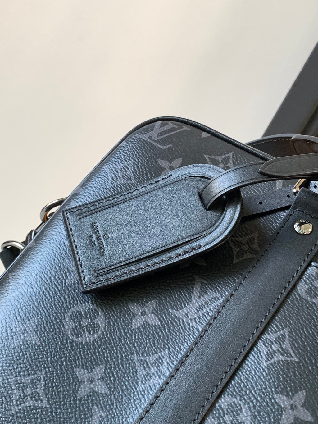 Dark monogram handbag close-up of leather flap pocket and crossbody strap
