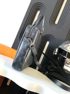 Handbag side view in dark monogram canvas with silver tone strap and handle rings