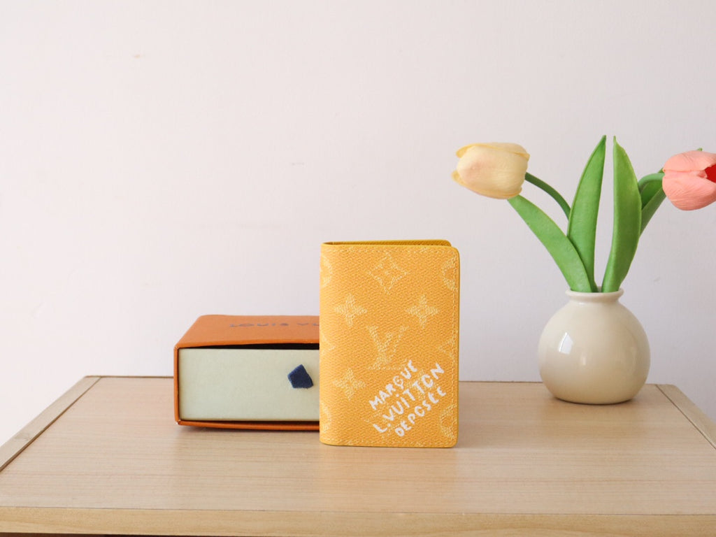 Yellow Louis Vuitton monogram small wallet/card holder standing on table