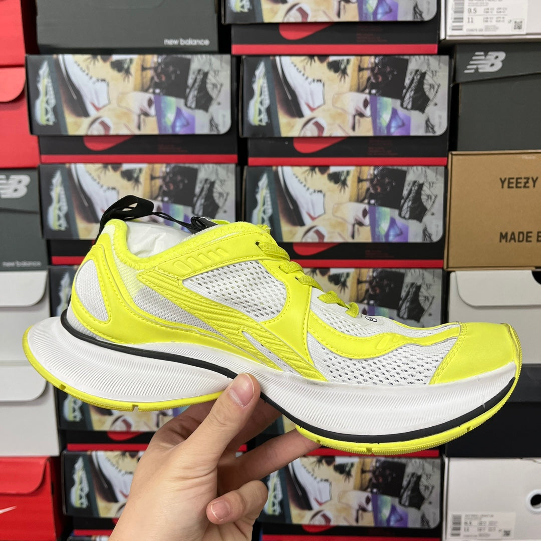 Neon yellow and white lace-up running shoe in hand, side view