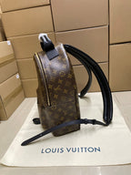 Monogram canvas backpack side view with black leather straps and hanging tag