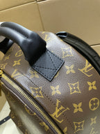 Monogram canvas backpack corner with black leather patch and gold zipper edge