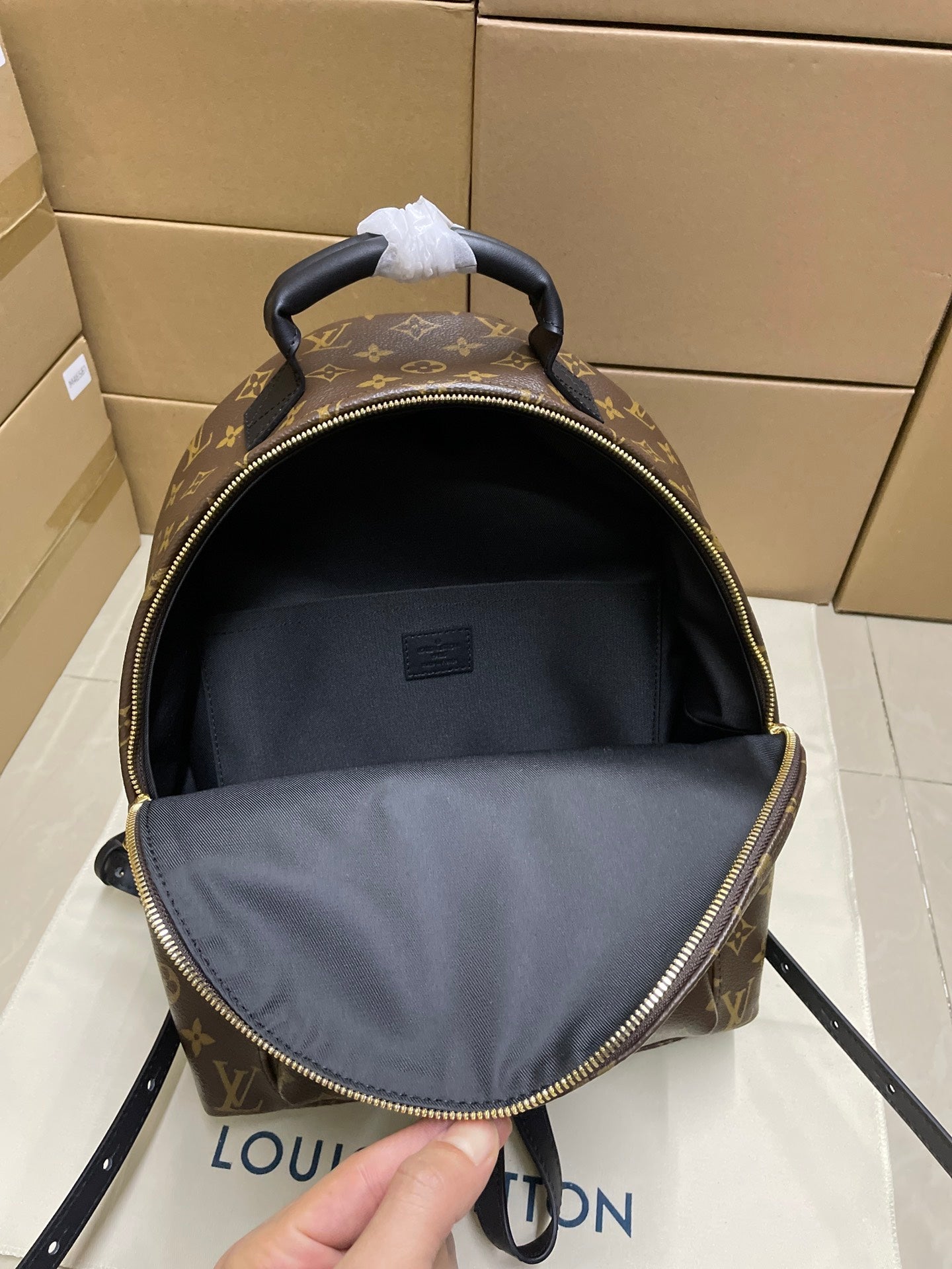 Monogram canvas backpack open with gray fabric lining and black top handle
