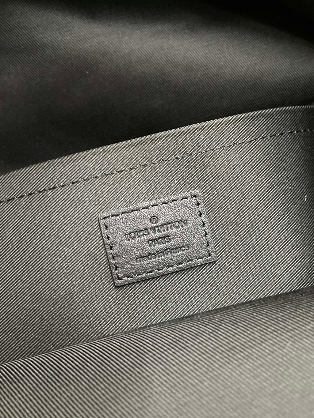 Gray fabric lining with embossed Louis Vuitton brand patch and stitching