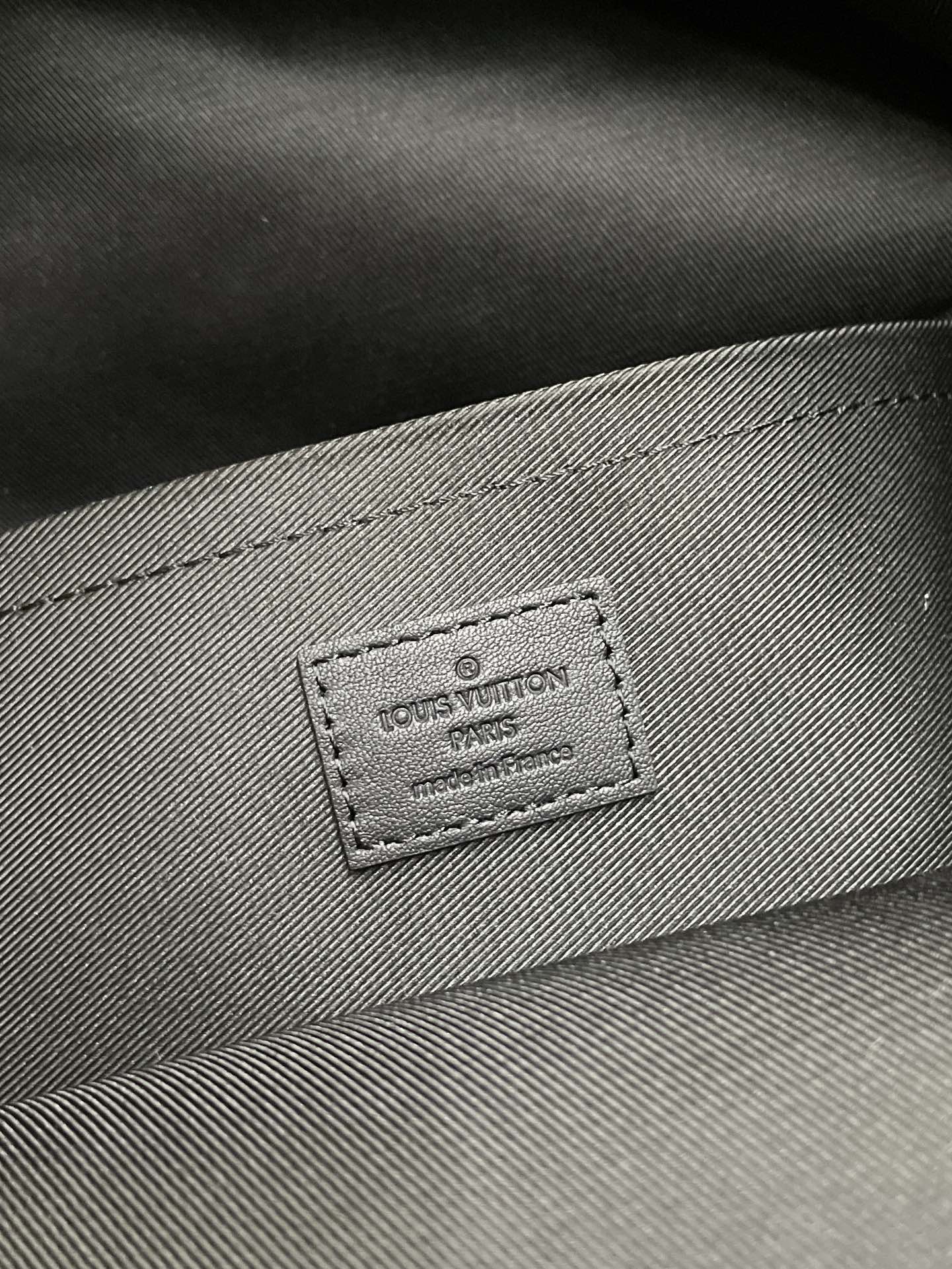 Gray fabric lining with embossed Louis Vuitton brand patch and stitching