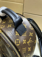 Monogram mini bag corner close-up with black leather tab and zipper on brown canvas