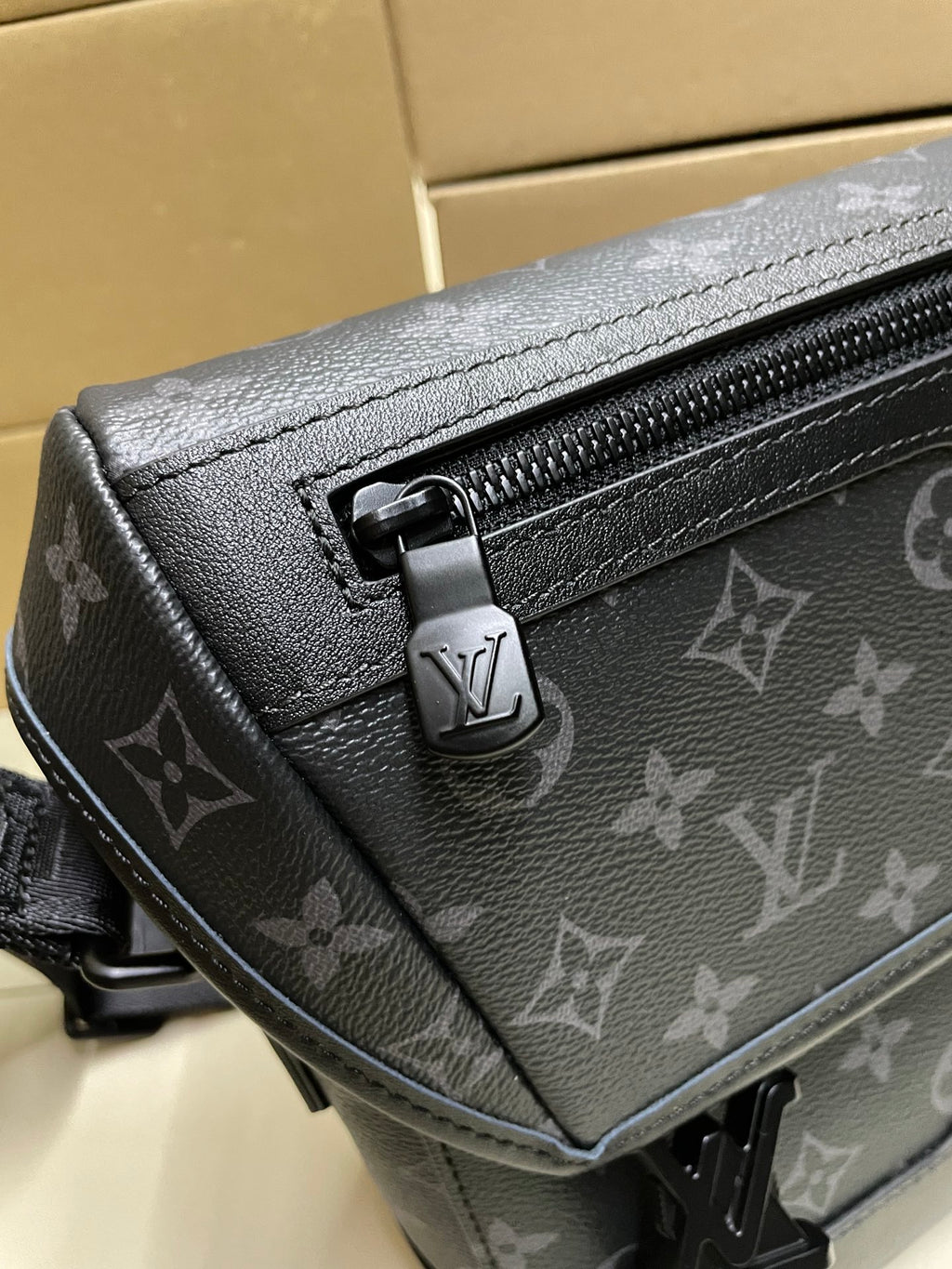 Men’s monogram crossbody bag close-up of metal clasp and zipper track
