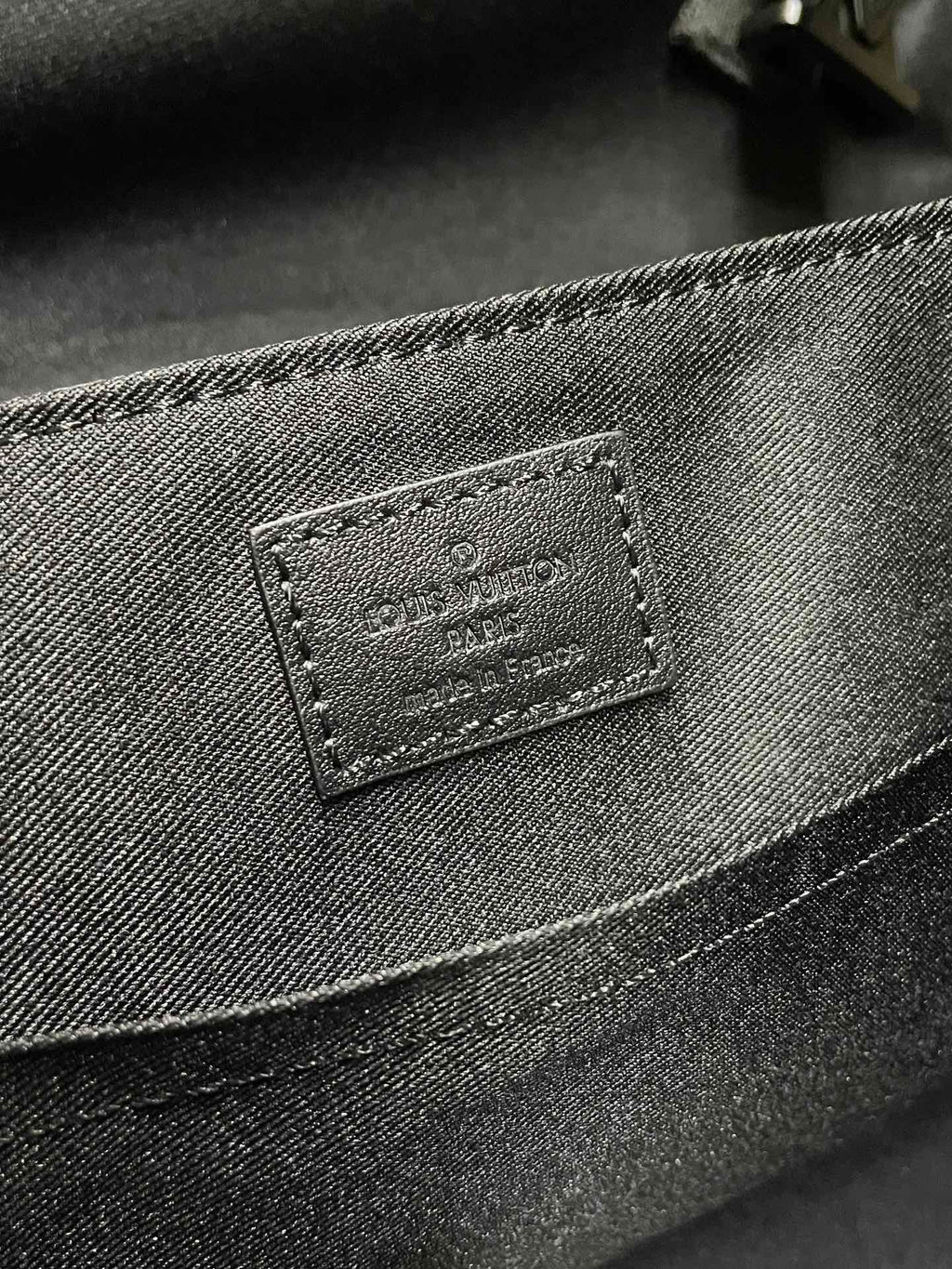 Men’s monogram bag close-up of rectangular leather label on front panel