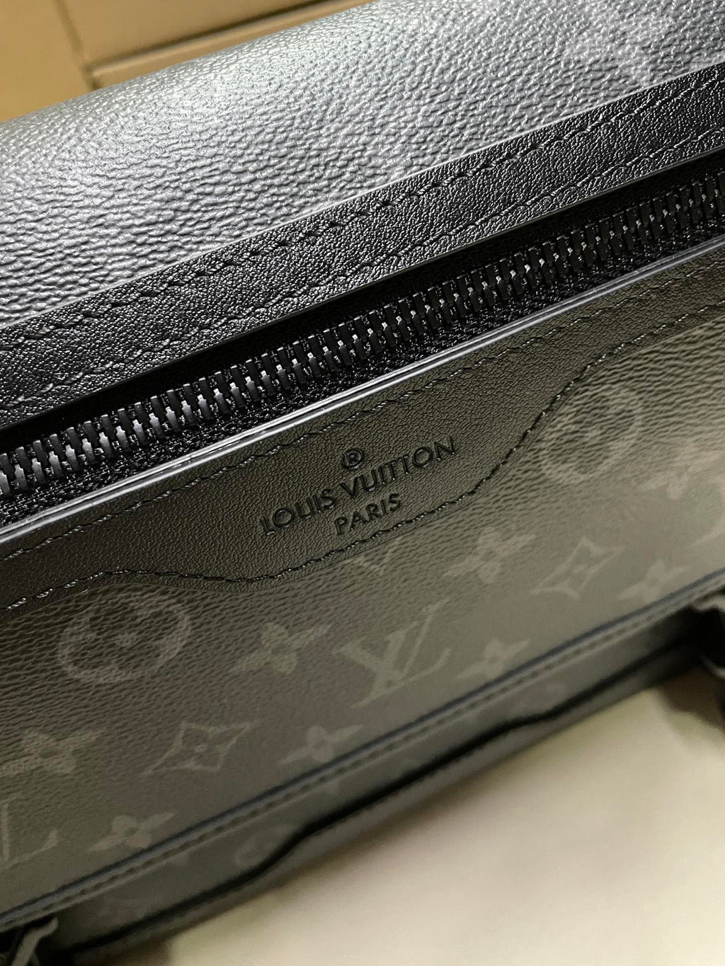 Men’s monogram bag close-up of zipper and embossed Louis Vuitton label on flap