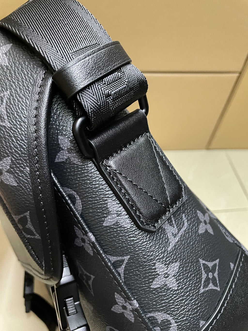 Men’s monogram bag close-up of shoulder strap and stitched strap tab