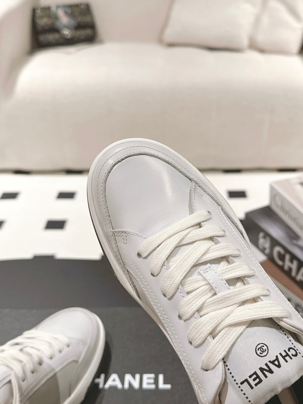 White leather sneaker toe with lace-up front, showing Chanel logo on tongue