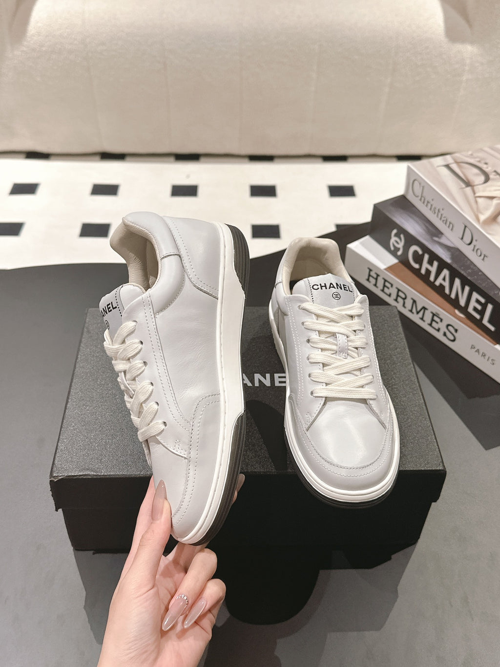 White leather low-top sneaker held by hand, thick rubber sole and laces
