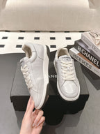 White leather low-top sneaker held by hand, thick rubber sole and laces