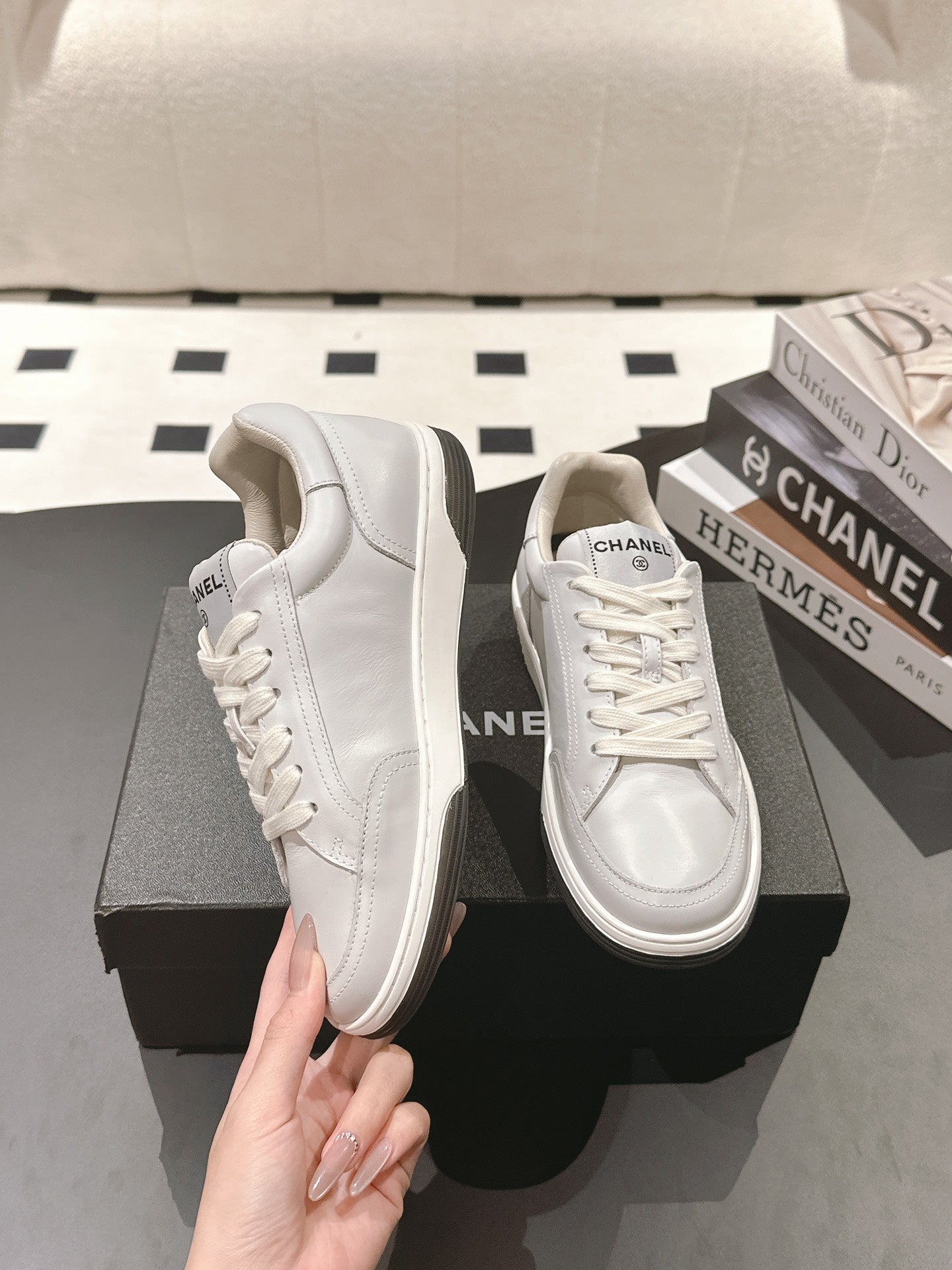 White leather low-top sneaker held by hand, thick rubber sole and laces