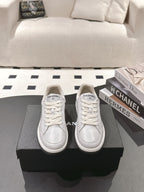 Pair of white leather low-top sneakers with lace-up vamps and Chanel logo