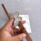 Silver butterfly buckle on a brown leather belt with adjustable strap holes