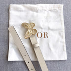 Light beige belt with gold butterfly buckle, pin closure, and eyelet holes