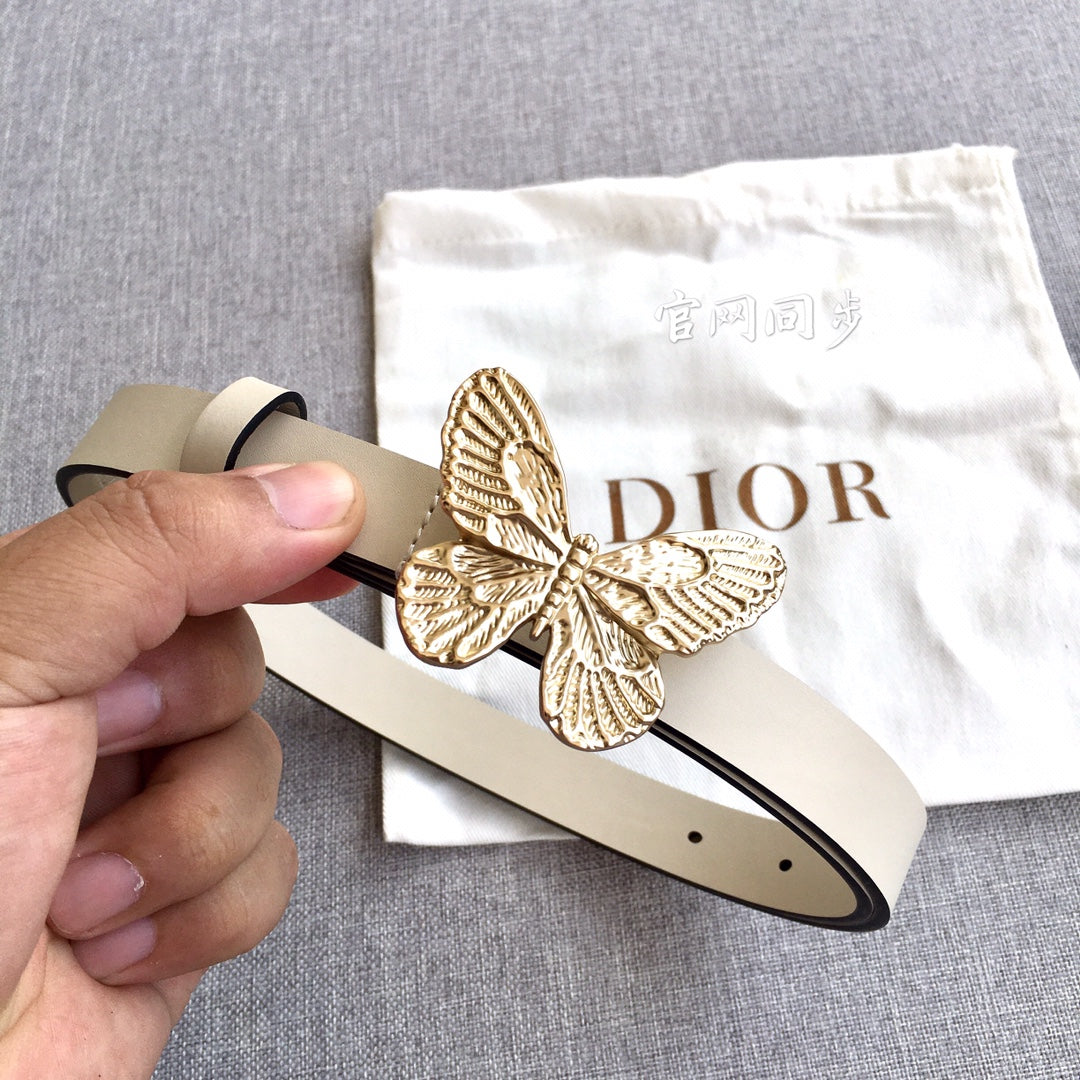 Light beige belt held by hand with gold butterfly buckle and pin closure