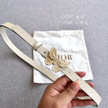 Light beige belt with gold butterfly buckle, pin closure and eyelet holes