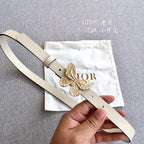 Light beige belt with gold butterfly buckle, pin closure and eyelet holes