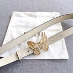 Light beige belt with gold butterfly buckle and stud holes, laid on a cloth pouch
