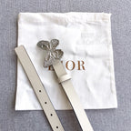 Cream leather belt with silver butterfly buckle and punched holes, side view