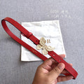 Red leather belt with gold-tone butterfly buckle, and punched adjustment holes.