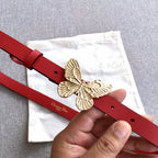 Red leather belt with gold-tone butterfly buckle and punched adjustment holes.