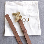 Dior belt flat lay: brown strap with gold butterfly buckle and end tabs