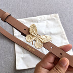 Dior belt close-up: brown strap with gold butterfly buckle and single metal hole
