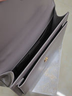 YSL bag interior view with side pocket lining and gold-tone snap hardware, gray-lavender