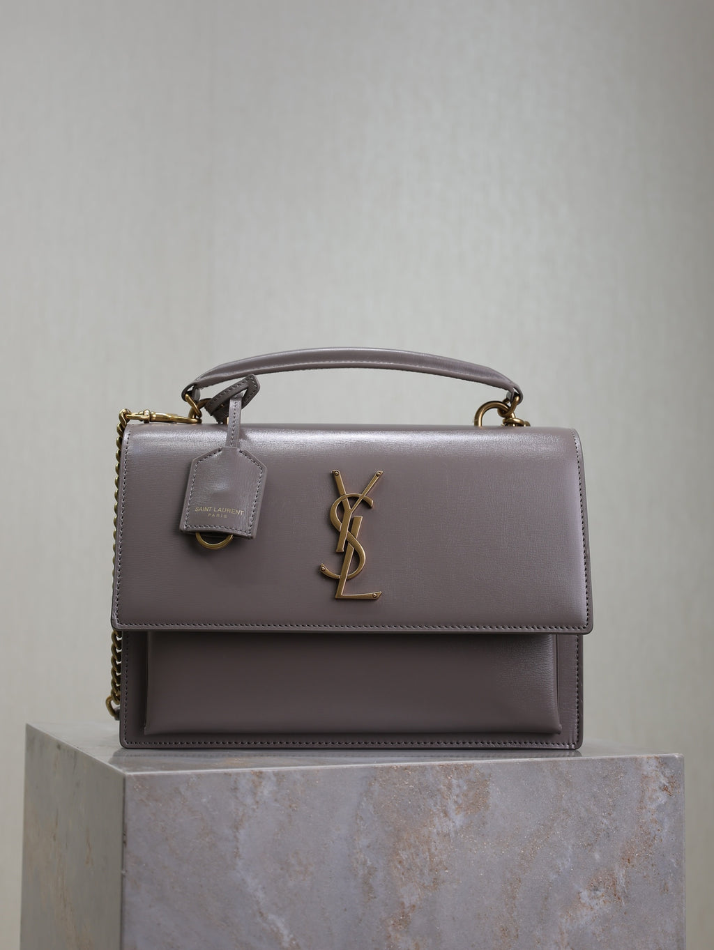 YSL bag with top handle, front flap, and gold-tone YSL logo hardware, gray-lavender