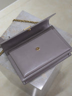 YSL bag back view with centered snap button and chain strap, gray-lavender leather