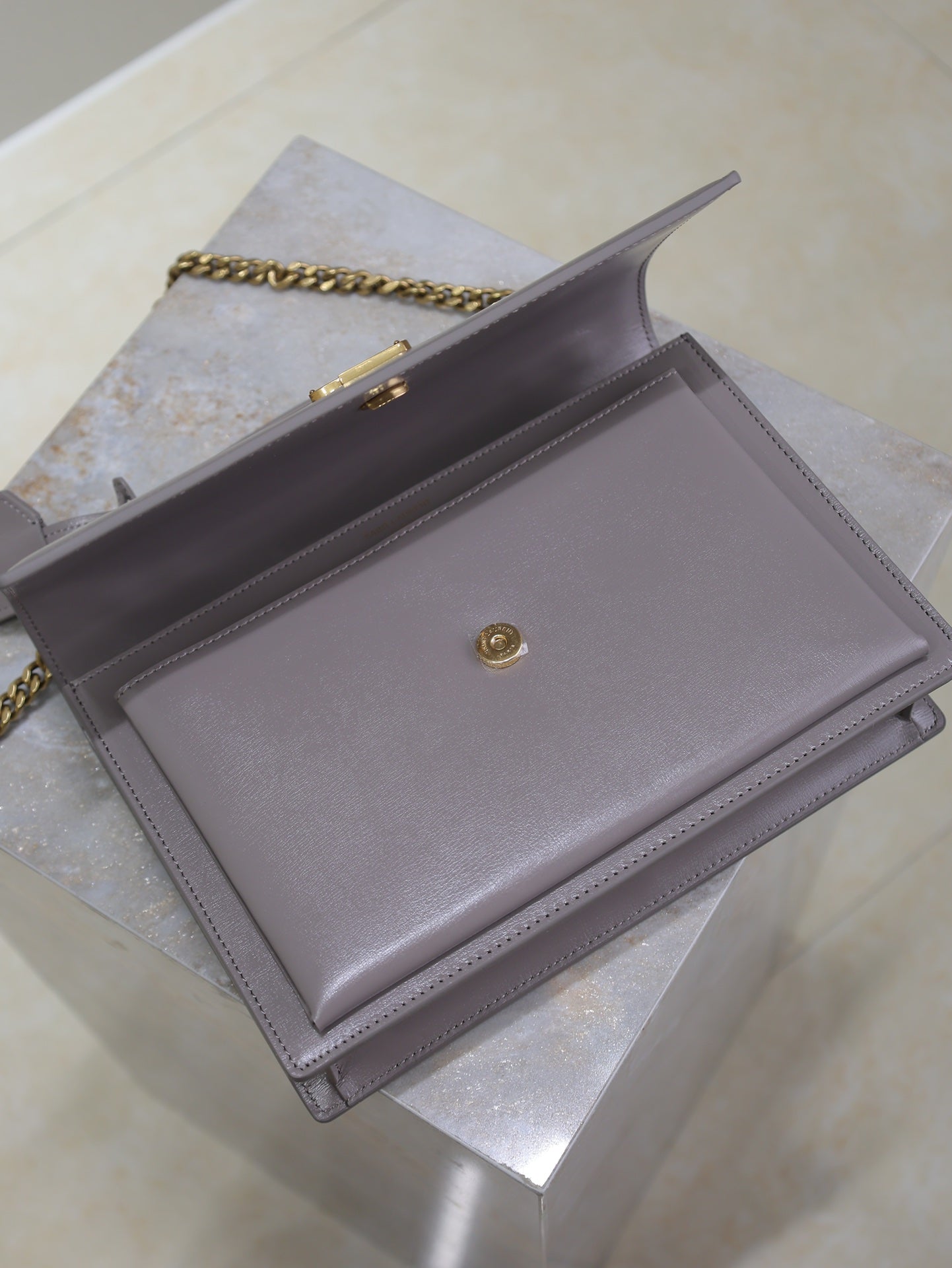 YSL bag back view with centered snap button and chain strap, gray-lavender leather