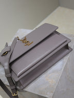 YSL bag stacked angle showing double flap design and gold-tone YSL logo, gray-lavender