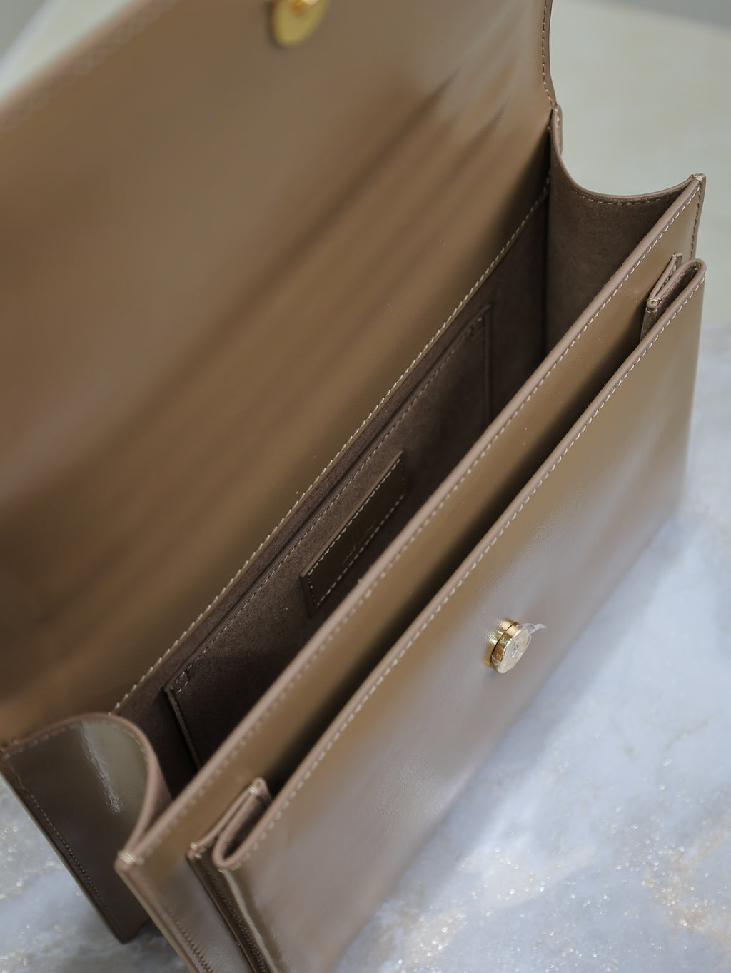 YSL tan bag interior with slip pocket, stitched edges, and snap tab
