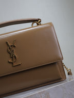 YSL tan flap bag detail with gold YSL logo and stitched front edge