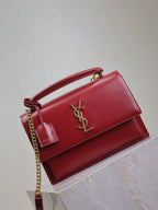 Red leather shoulder bag with gold YSL logo on front flap and chain strap.