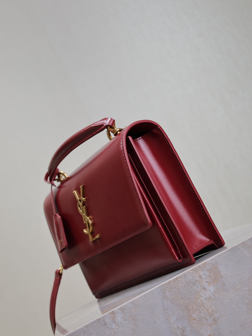 Red leather flap bag with top handle, gold hardware, and flap opened to side.