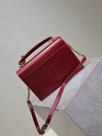 Red leather crossbody bag with chain strap and top handle, front flap closed.