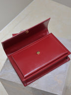 Red leather wallet-style bag with open flap and gold button closure.
