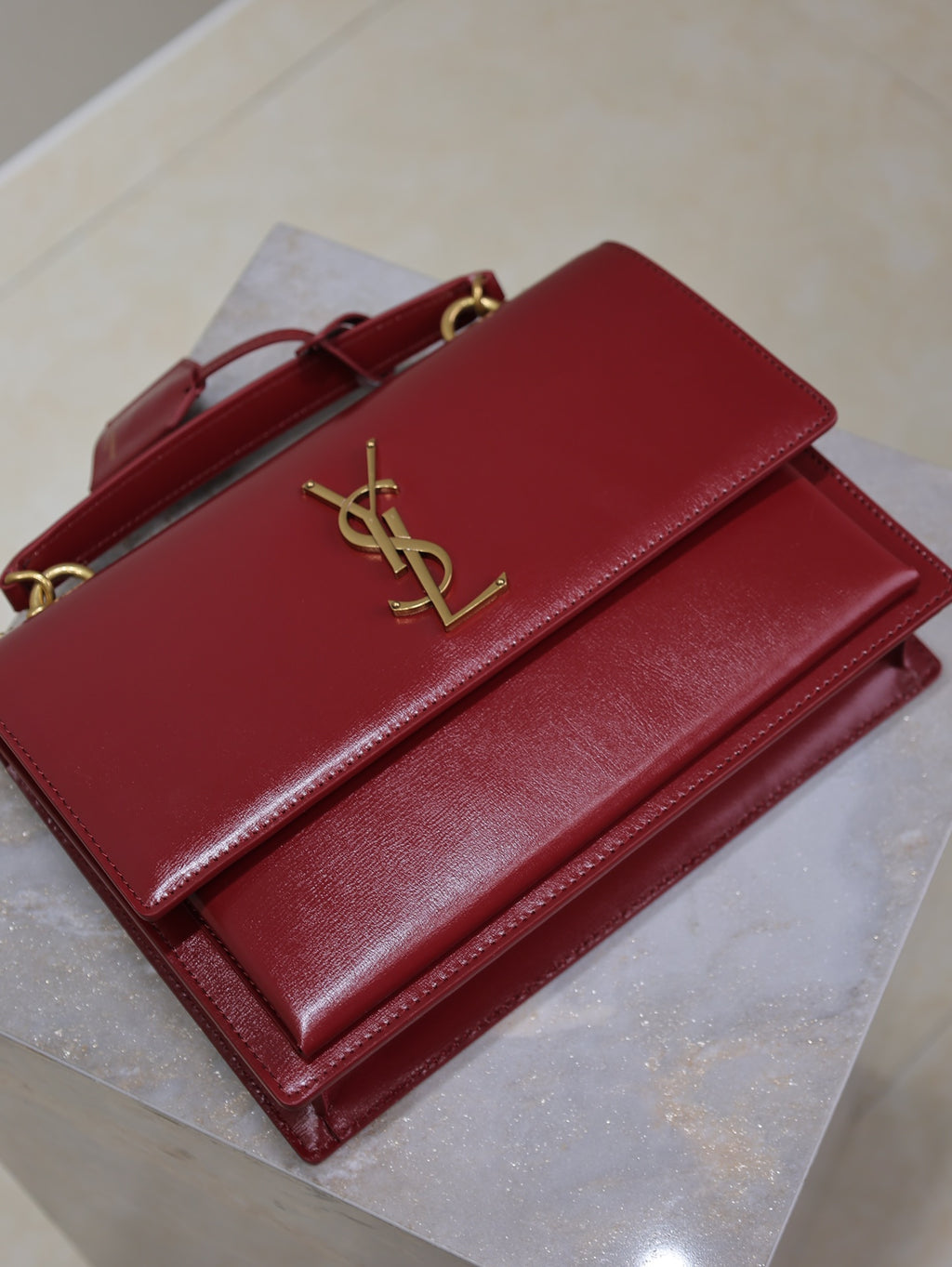 Red leather bag with front flap and gold YSL logo, open with inner compartments.