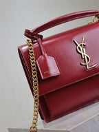 Red leather flap bag with gold chain, logo charm, and front YSL emblem.