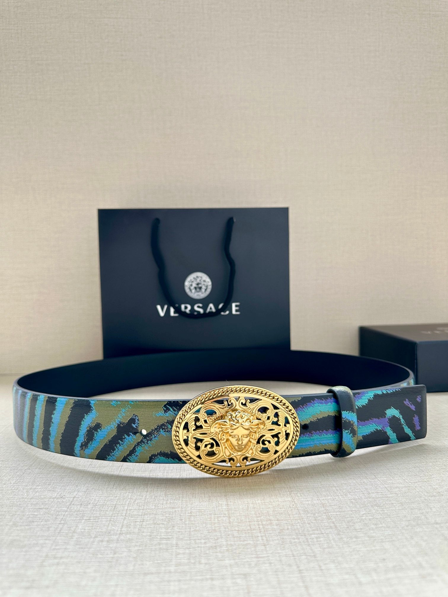 Versace belt with oval gold-tone buckle and blue-green patterned strap with dark edges