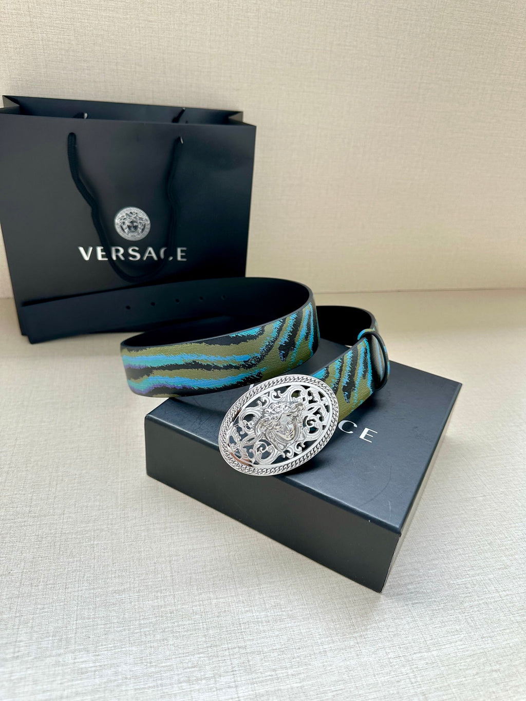 Versace belt close-up: oval silver-tone buckle on blue-green patterned strap