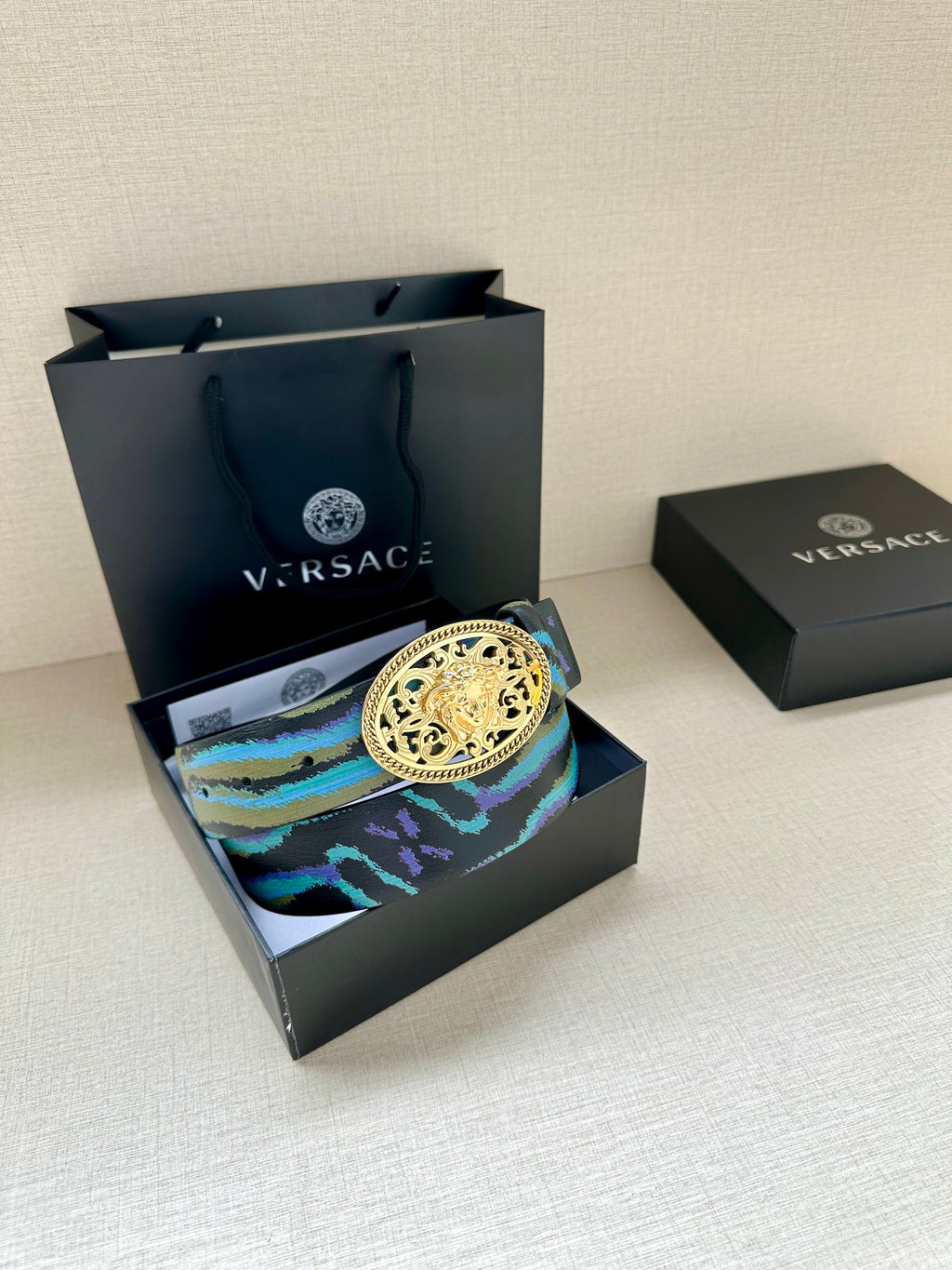 Versace belt on box: blue-green patterned strap with large oval gold-tone buckle