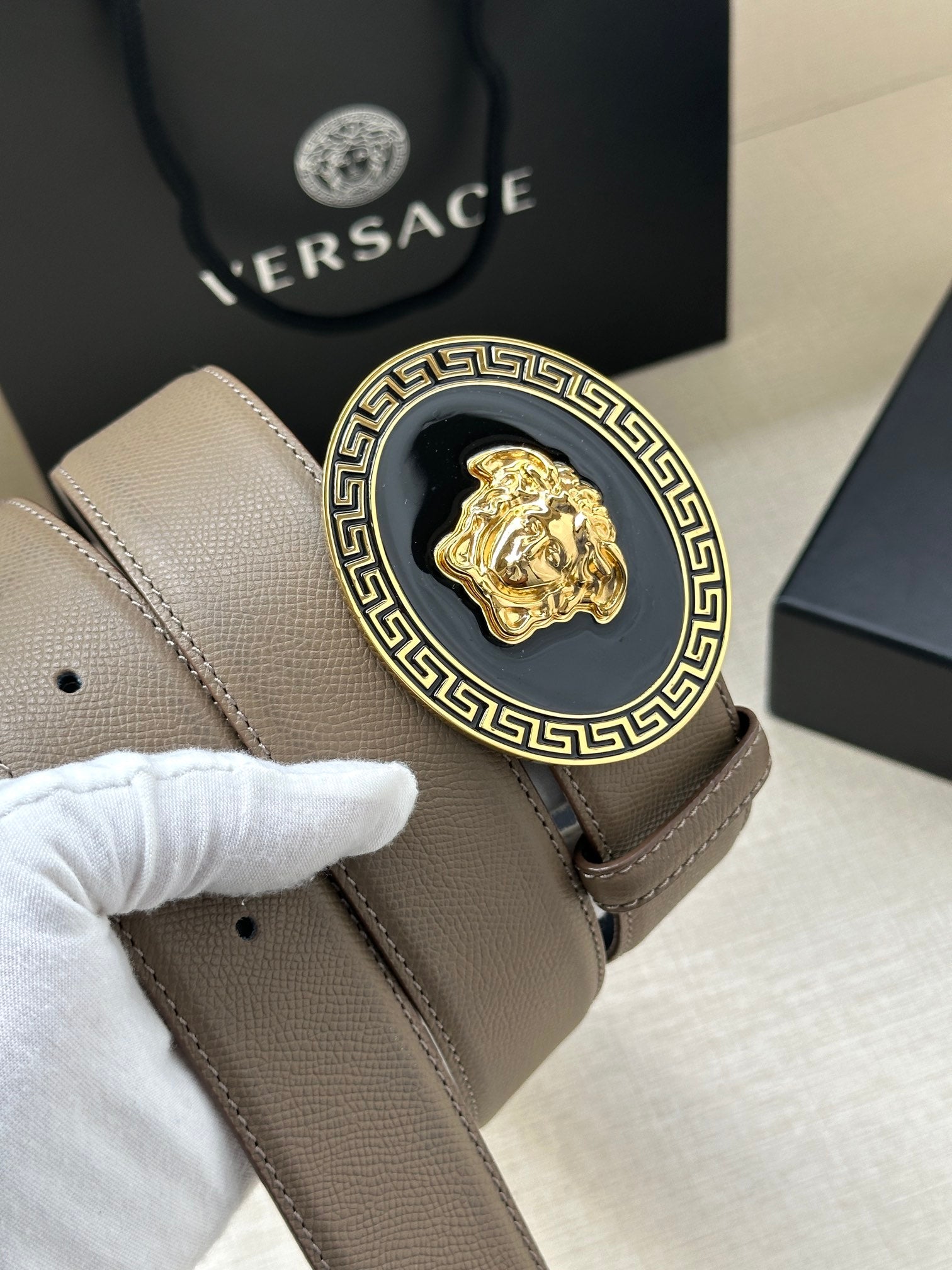 Leather belt detail showing light taupe buckle with Greca Medusa medallion
