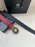 Close-up of maroon Versace belt strap with gold Greek key Medusa buckle