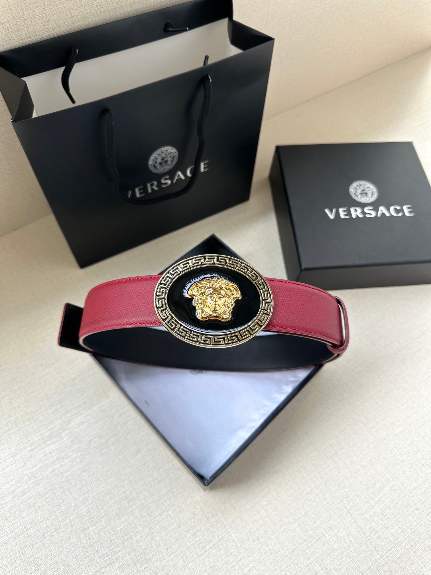 Maroon Versace belt with gold Medusa buckle and Greek key detailing, on box